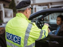 Young woman pulled over by police officer on the road. ...